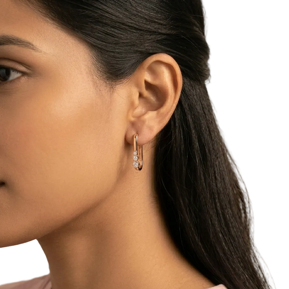 Close-up of a woman wearing gold hoop earrings with a neutral background